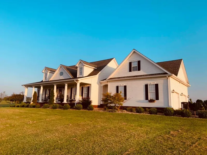 White farmhouse with a wraparound porch after cleaning