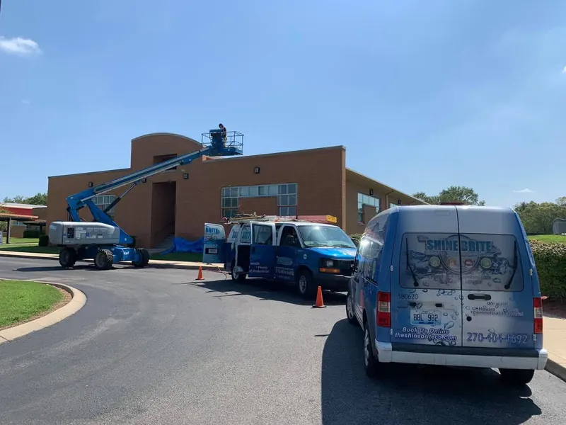 Boom lift and Shine Brite vans at a commercial building